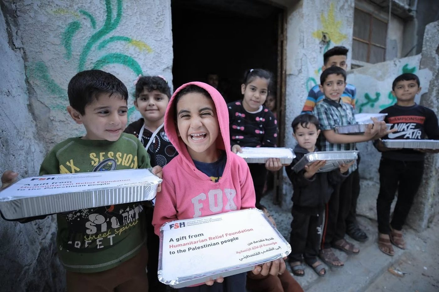 Children in Gaza smiling and holding FSH hot meal trays