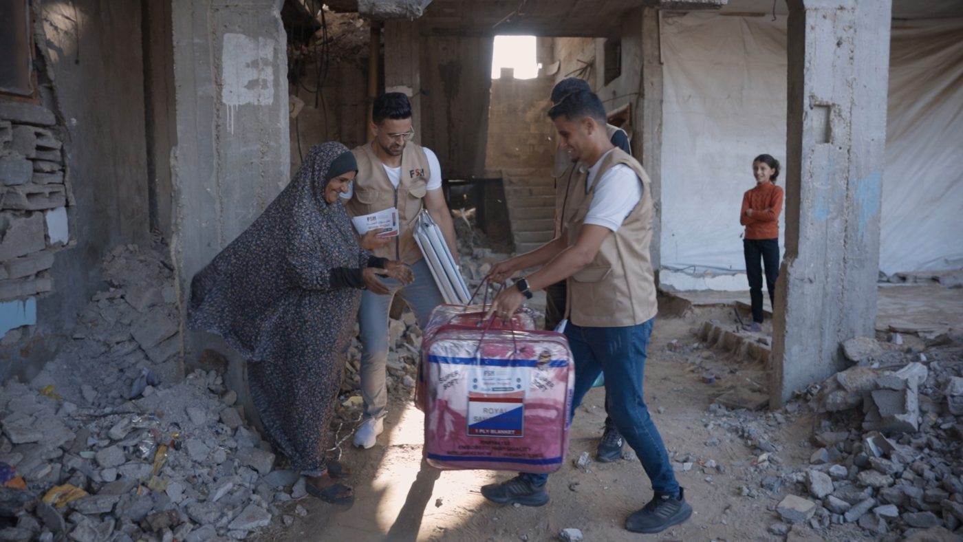 FSH team handing a blanket to a woman in Gaza