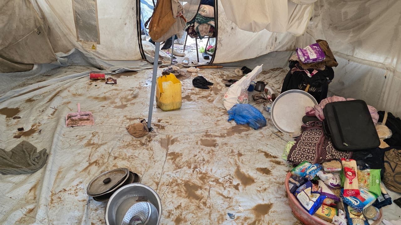 Tent floor covered in mud and water, a family's belongings scattered