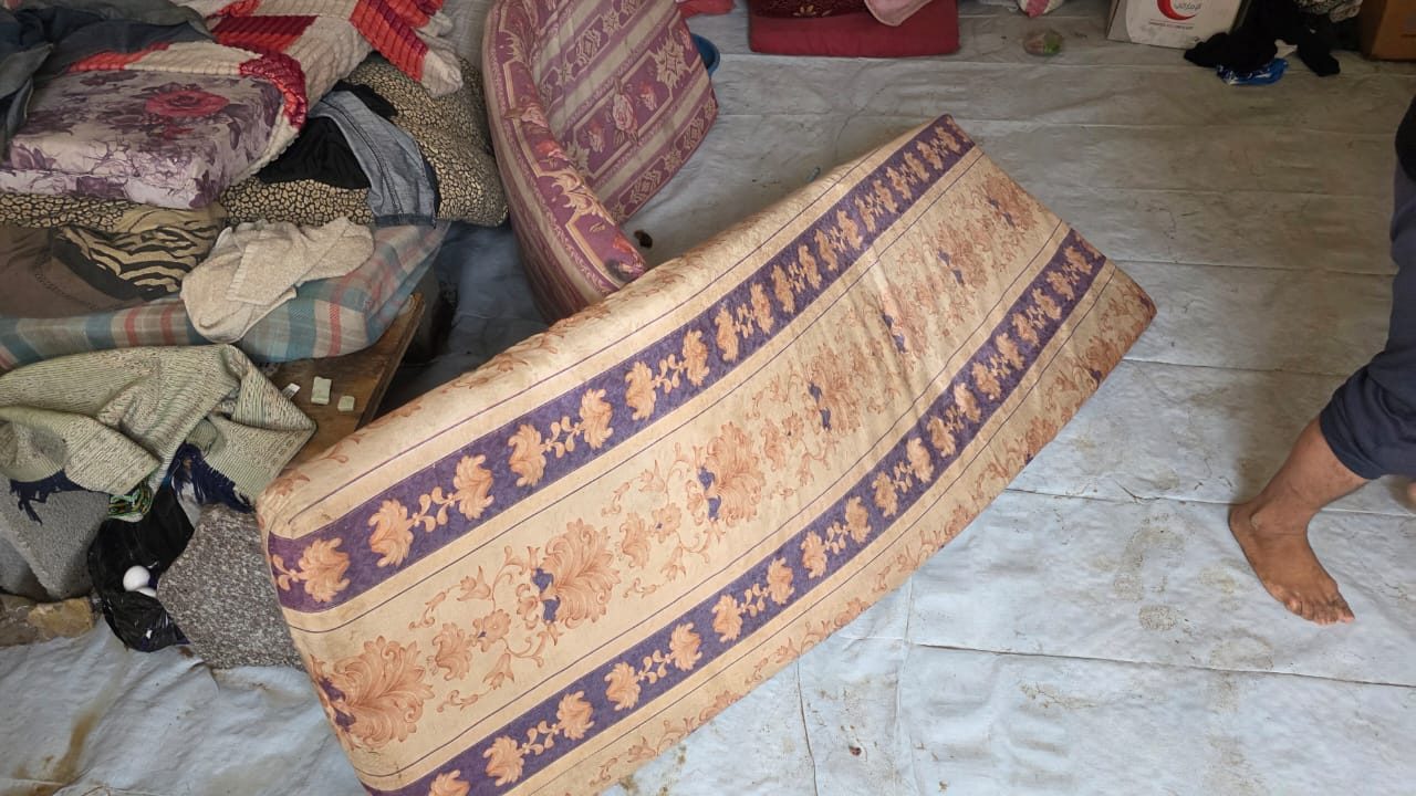 Soaked mattresses and bedding inside a tent after heavy rain