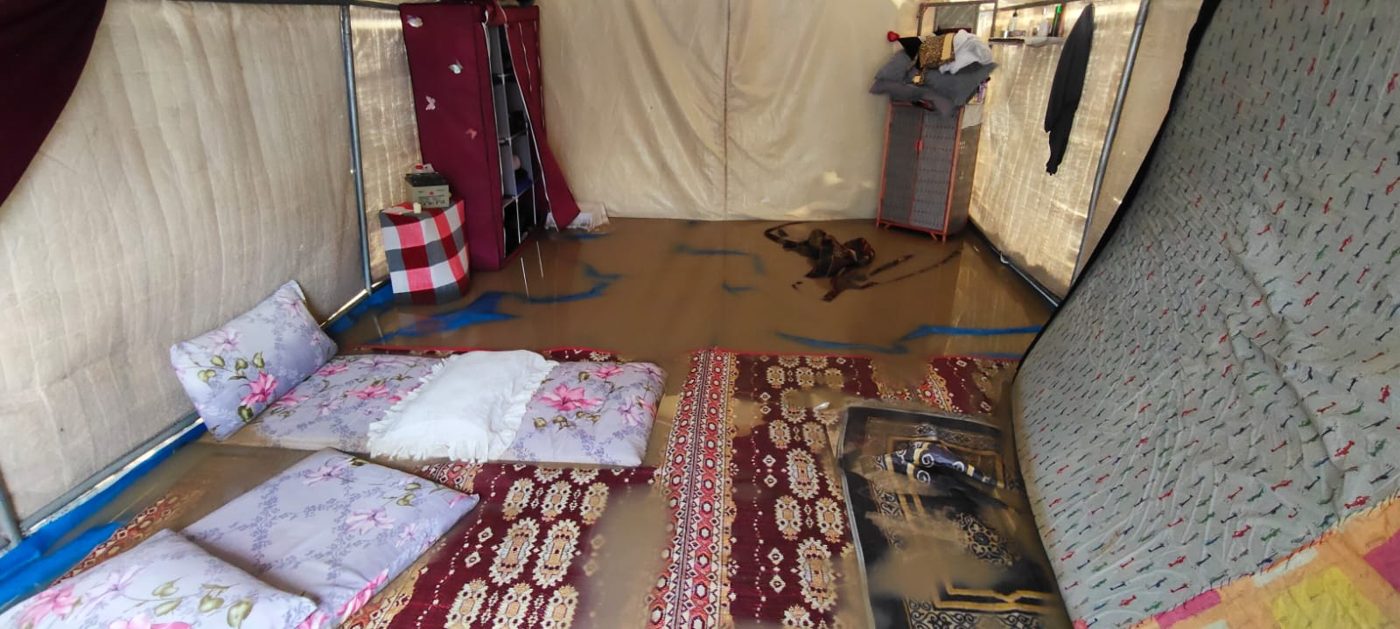 Rainwater flooding the floor of a displaced family's tent