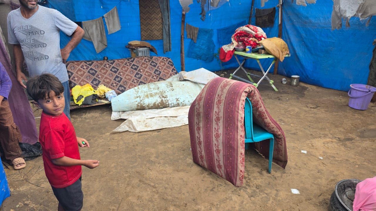 A boy in a Gaza camp standing beside his family's soaked mattresses after the rain