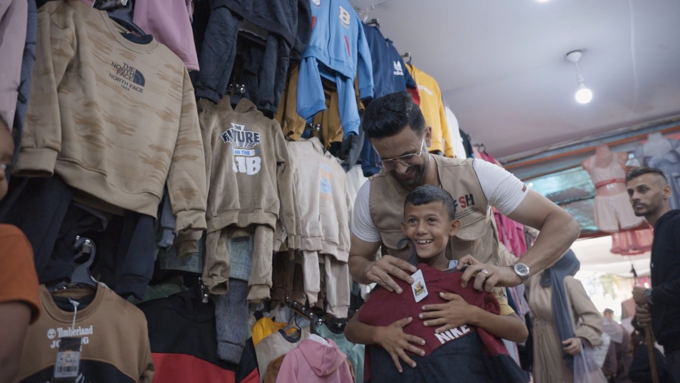 A boy trying on a winter sweater in a local clothing shop in Gaza